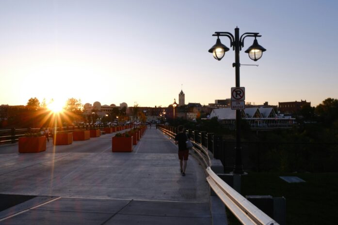 A person walking on a bridge at sunset