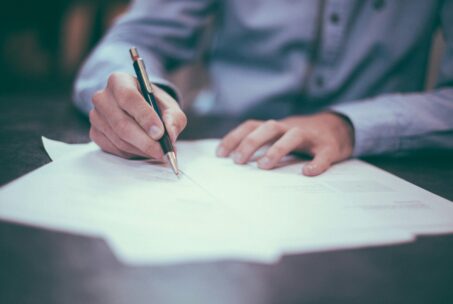 Person filling out forms with a pen